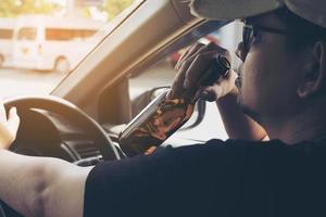 Man drinking beer while driving a car photo