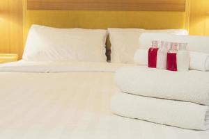 Hotel towel with shampoo and soap bottle set on white bed photo