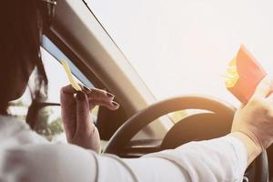 Lady eating french fries white driving car dangerously photo