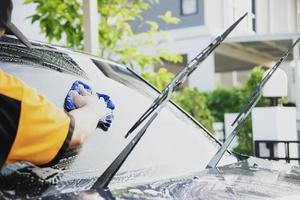 El hombre lava el coche con champú - concepto de cuidado del coche de la vida cotidiana foto