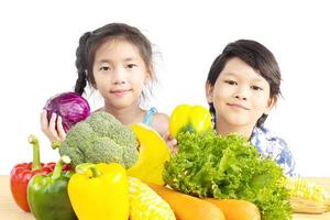 Asian boy and girl showing enjoy expression with fresh colorful vegetables isolated over white background photo