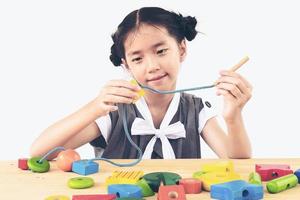 Lovely asian girl is play colorful wood block toy photo