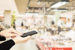 Man using mobile phone over blurred superstore background photo