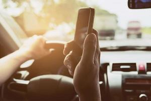 primer plano de un hombre conduciendo un coche peligrosamente mientras usa el teléfono móvil foto