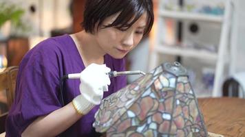 A woman making a stained glass lamp