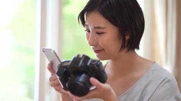 una donna che guarda le immagini scattate con una fotocamera reflex a obiettivo singolo e uno smartphone video