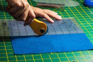 Cloth cutting process - woman's hands using rotary cutter for her patchwork photo