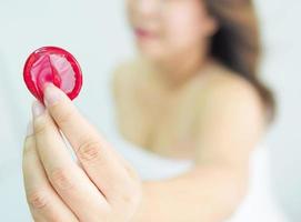 Lady is giving red condom, safe sex and contraception concept. photo