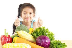 Encantadora chica asiática mostrando disfrutar de la expresión con verduras frescas y coloridas aislado sobre fondo blanco. foto