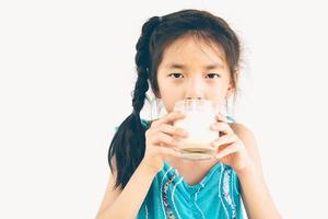 foto de estilo vintage de una chica asiática está bebiendo un vaso de leche sobre fondo blanco