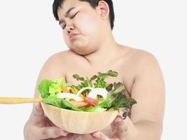 A fat boy hate to eat vegetable salad photo