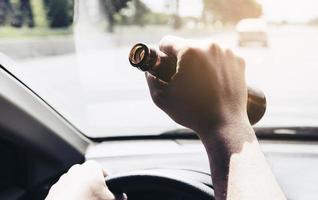 Man holding beer bottle while driving a car photo