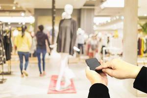 Man using mobile phone over blurred superstore background photo