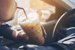 Man is dangerously drinking cup of cold coffee while driving a car photo