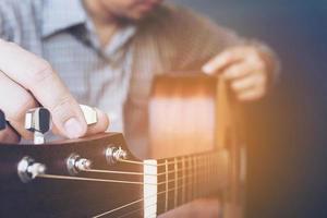 Man tuning acoustic guitar photo