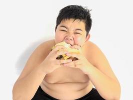 un chico gordo está felizmente comiendo un sándwich. foto