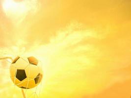 Football in goal net with warm yellow sky background photo