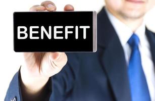 BENEFIT, word on mobile phone screen in blurred young businessman hand over white background, business concept photo