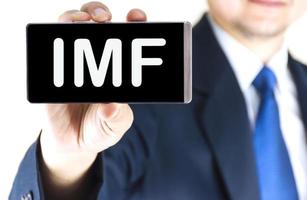 IMF, International Monetary Fund, word on mobile phone screen in blurred young businessman hand over white background, business concept photo