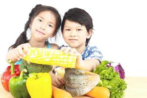 Asian boy and girl showing enjoy expression with fresh colorful vegetables isolated over white background photo