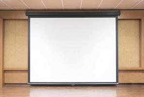 Front view of lecture room with empty white projector screen photo