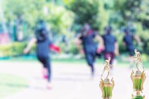 Trofeo del día del deporte sobre una colegiala borrosa corriendo durante la carrera de relevos foto