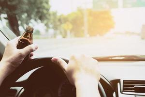 Man holding energy drink bottle while driving a car photo