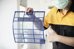 Air conditioner maintenance man showing cleaned filter after cleaning during hot season in Thailand photo