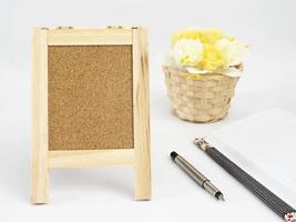 Diary and pen with small stand notice board and white rose basket over white background photo