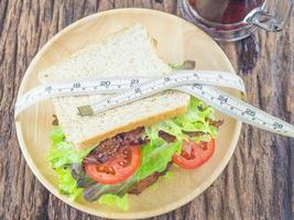 sándwich con refresco frío y cinta métrica como concepto de dieta foto