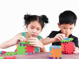 Asian children are playing puzzle plastic block creative game to practice their physical and mental skill photo