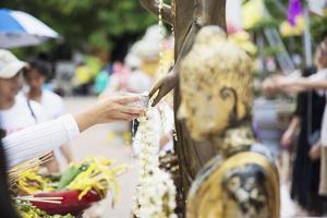 personas vertiendo agua sobre una imagen de buda este es un gesto de adoración: las personas participan en el festival tradicional budista anual local de chiang mai. foto