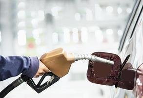 hombre poniendo gasolina en su coche en una gasolinera de bomba foto