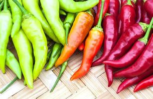 Mixed color chilli on weave bamboo background photo