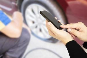 el hombre está usando un teléfono móvil llamando a alguien sobre el fondo de un neumático desinflado foto