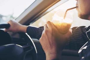 Man is dangerously drinking cup of cold coffee while driving a car photo