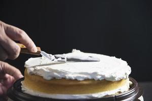 señora haciendo pastel poniendo crema con espátula - concepto de cocina de panadería casera foto