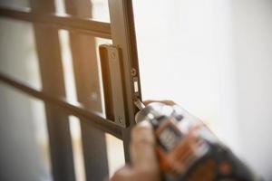 hombre haciendo marco de aluminio con gafas y trabajo de instalación de puertas y ventanas de pantalla de alambre en el sitio de construcción foto