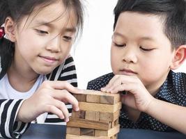 los niños juegan jenga, un juego de torre de bloques de madera para practicar su habilidad física y mental foto