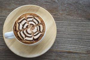Vintage hot coffee cup with nice Latte art decoration on old wooden texture table photo