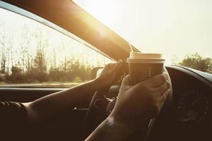 dama conduciendo un auto mientras sostiene una taza de café foto