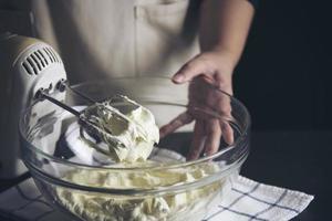 señora haciendo pastel poniendo crema con espátula - concepto de cocina de panadería casera foto