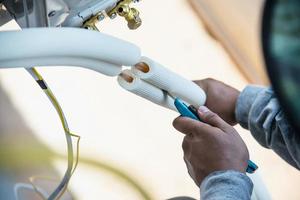 Man is installing wall compressor of air conditioner during hot season photo