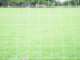 Soccer goal net with green field background photo