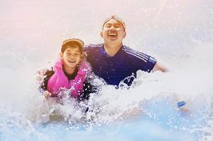 Happy brother playing in clean blue sea with wave splash photo