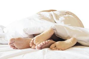 Couple on white bed in hotel room focus at feet photo