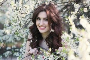 hermosa chica europea blanca con piel limpia en el parque con árboles en flor foto