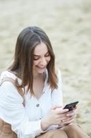 Girl outdoors texting on her mobile phone. Girl with phone. Portrait of a happy woman text sms message on her phone. photo
