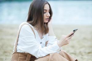 Girl outdoors texting on her mobile phone. Girl with phone. Portrait of a happy woman text sms message on her phone. photo