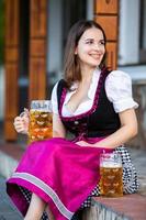 Sexy russian woman in Bavarian dress holding beer mugs. photo